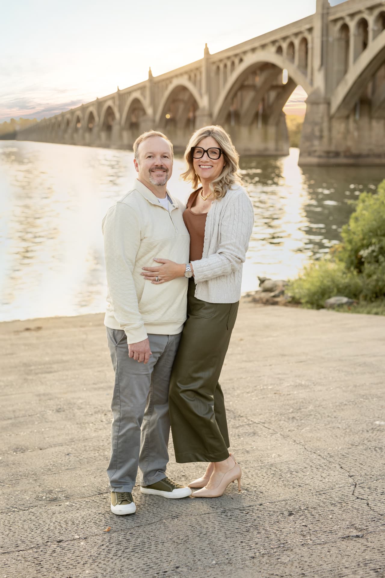 Corie Adams and her husband Matt standing together by the river at sunset